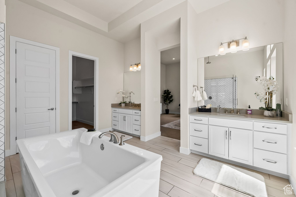 Bathroom featuring a raised ceiling, double vanity, and a bath