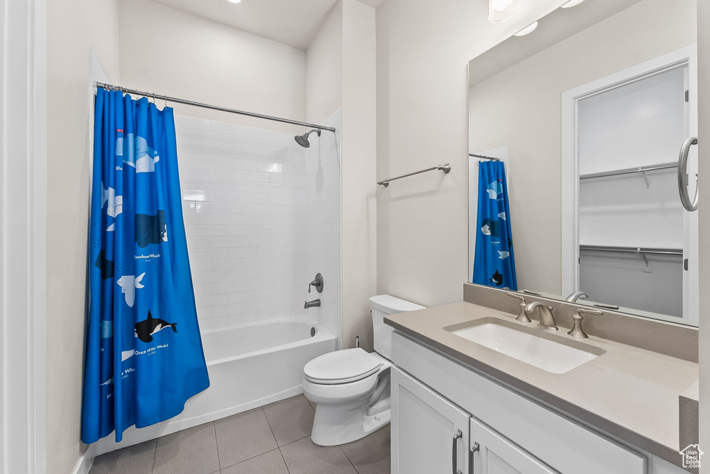 Full bathroom featuring tile flooring, oversized vanity, shower / bath combination with curtain, and toilet