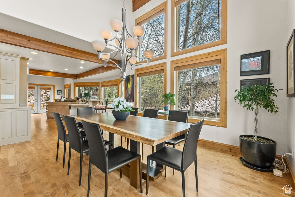 Dining space featuring light hardwood / wood-style floors, beamed ceiling, and a notable chandelier