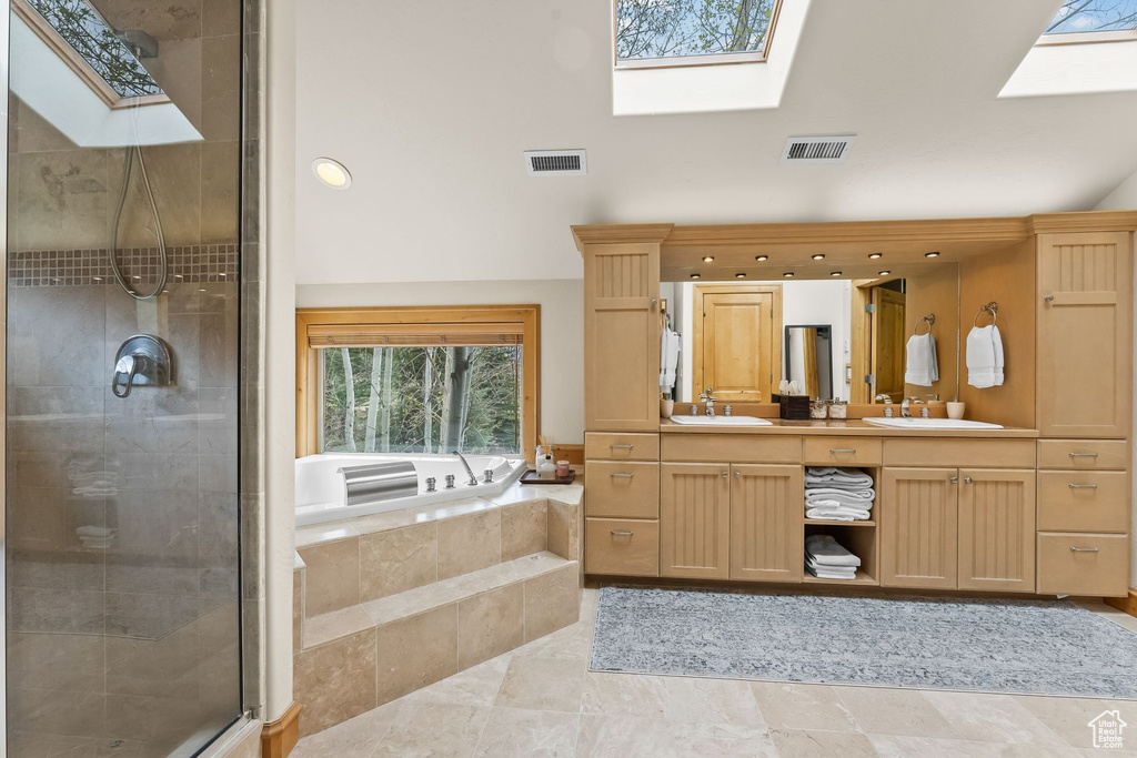 Bathroom with a skylight, tile floors, double vanity, and shower with separate bathtub