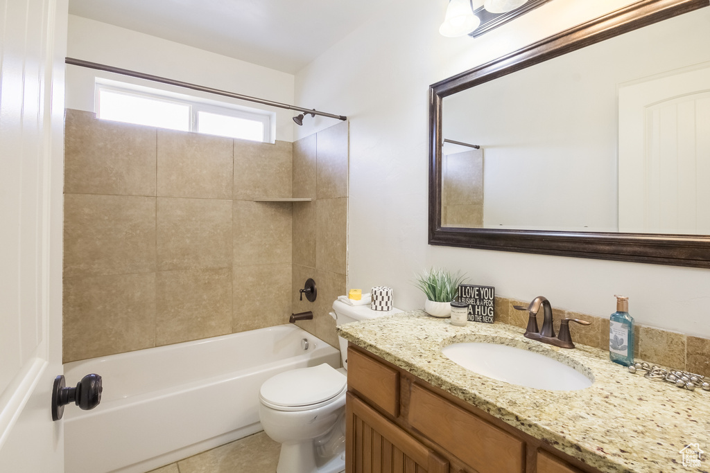 Full bathroom with tile flooring, vanity, tiled shower / bath combo, and toilet