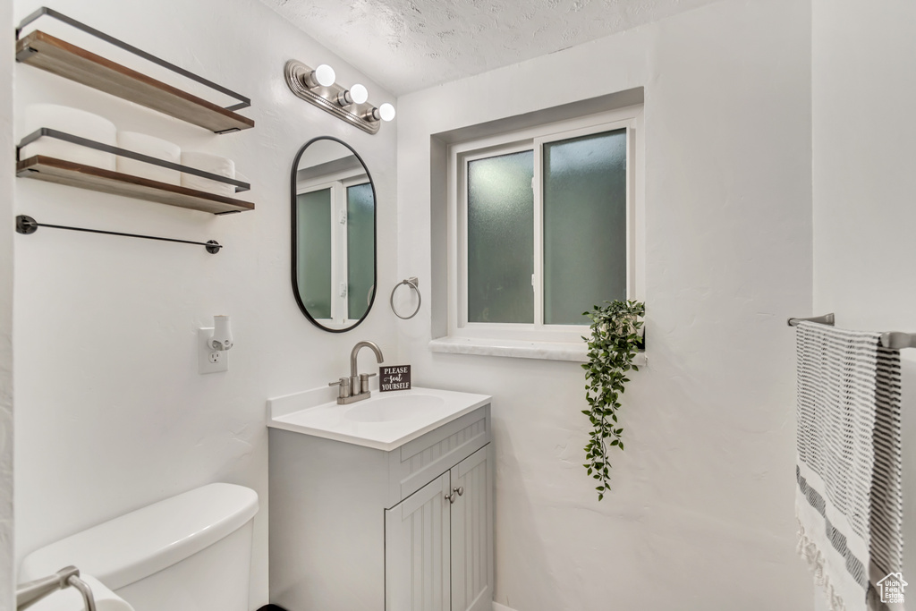 Bathroom with toilet, oversized vanity, and a textured ceiling