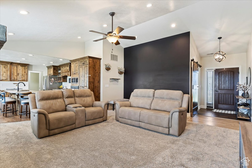 Carpeted living room with high vaulted ceiling, ceiling fan, and a barn door