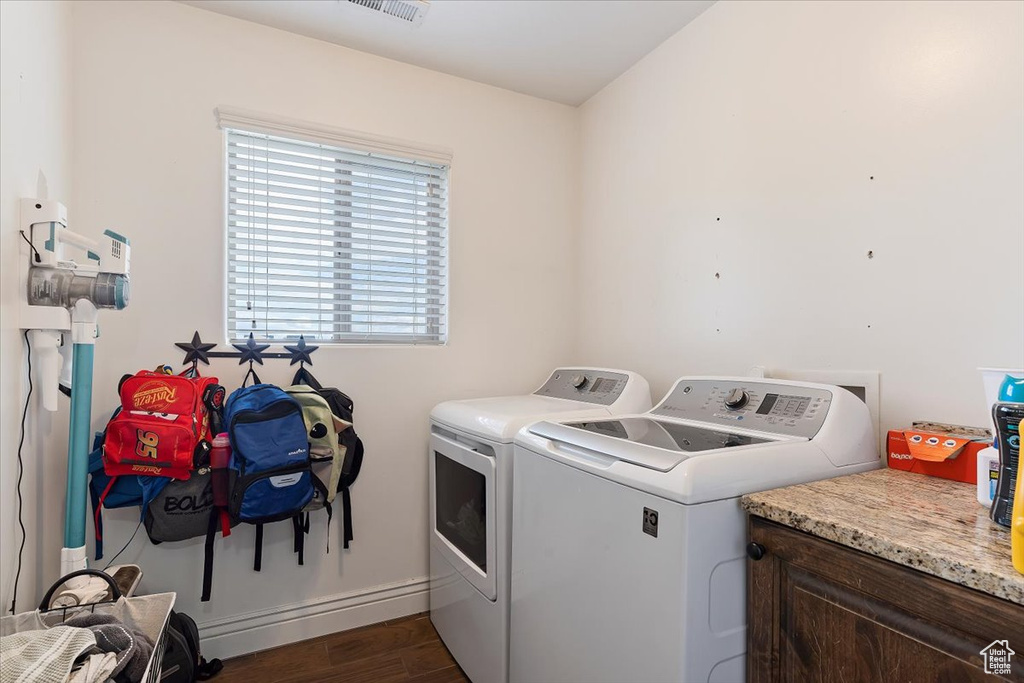 Washroom with dark wood-type flooring and washing machine and clothes dryer