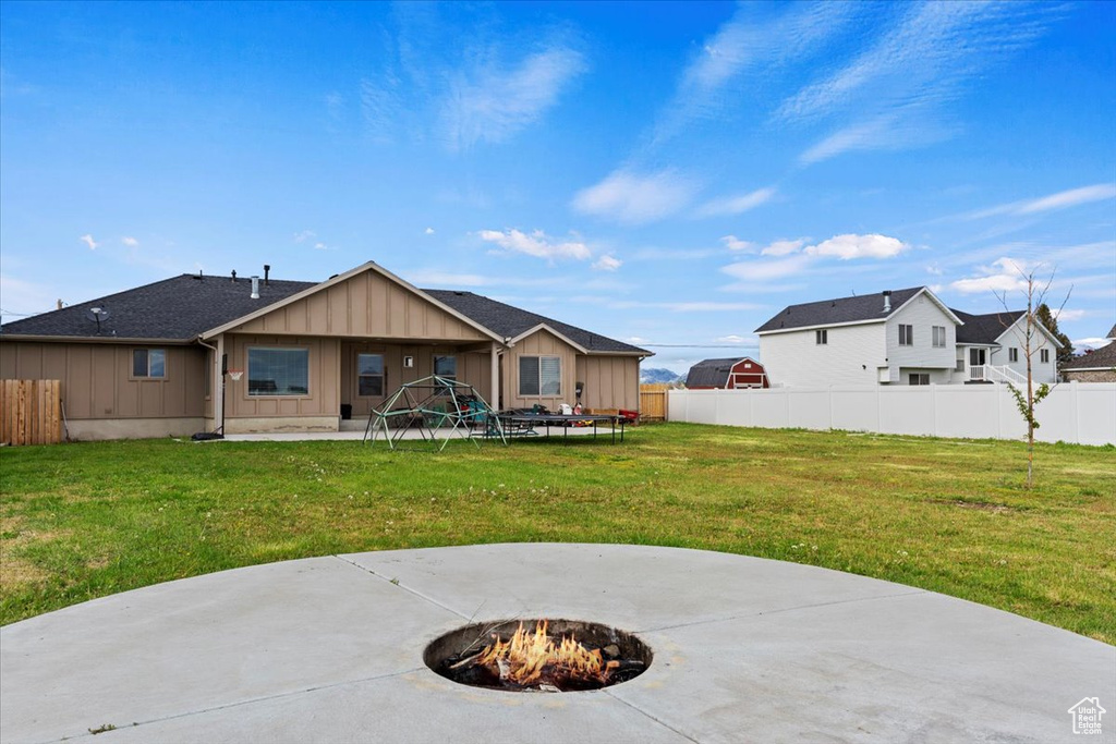 Back of house featuring a patio area, an outdoor fire pit, and a lawn