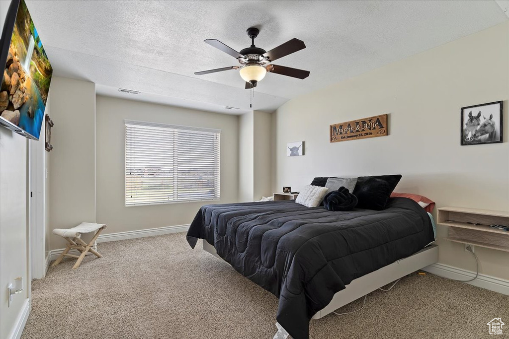 Carpeted bedroom with ceiling fan and a textured ceiling