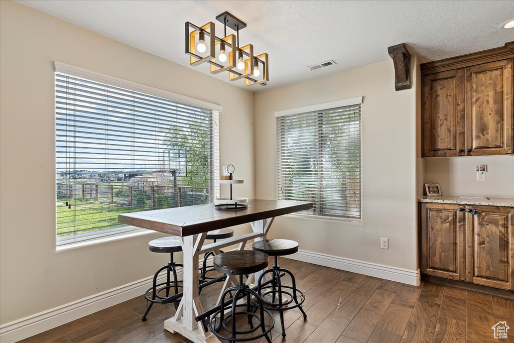 Dining area with dark hardwood / wood-style flooring, a wealth of natural light, and a notable chandelier