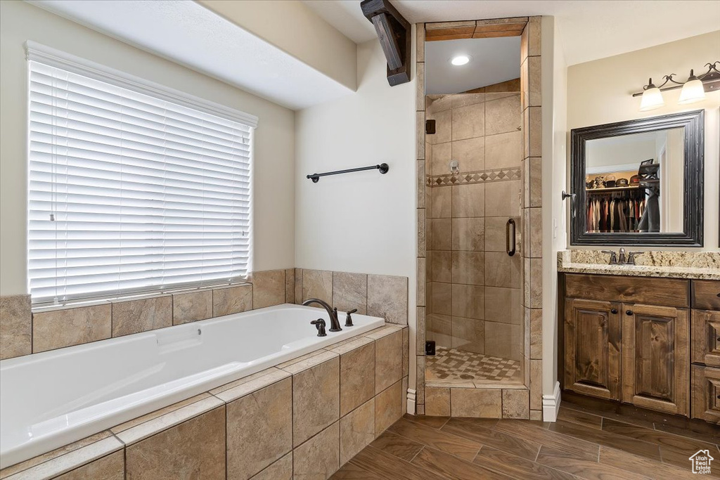 Bathroom featuring shower with separate bathtub and vanity