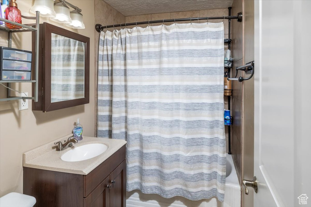 Full bathroom featuring oversized vanity, shower / bath combo, and toilet