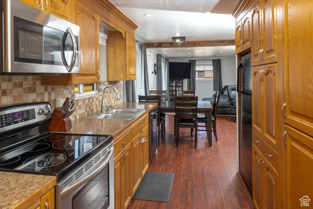 Kitchen featuring backsplash, sink, stainless steel appliances, and dark hardwood / wood-style flooring