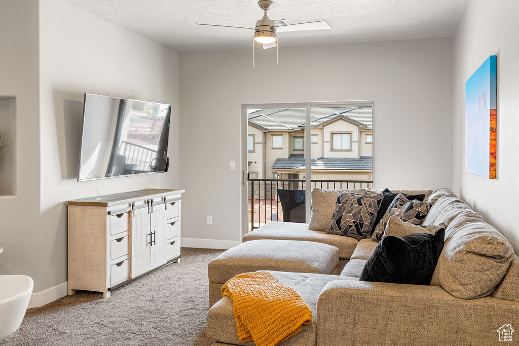 Living room featuring a textured ceiling, ceiling fan, and light carpet