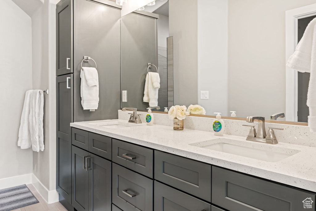 Bathroom with double vanity and wood-type flooring