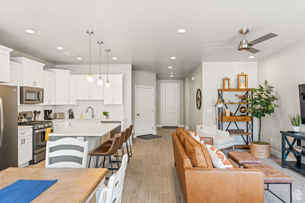 Kitchen with a center island, pendant lighting, backsplash, stainless steel appliances, and ceiling fan