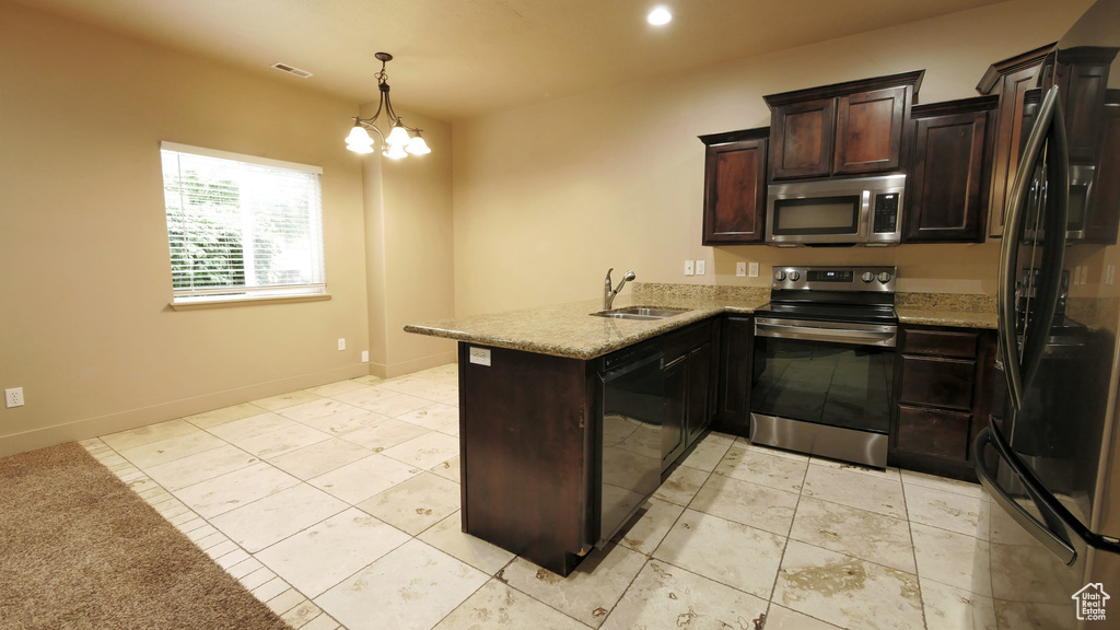 Kitchen featuring kitchen peninsula, hanging light fixtures, black appliances, sink, and light tile floors