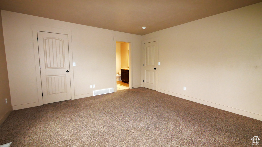 Unfurnished bedroom featuring ensuite bath and carpet flooring