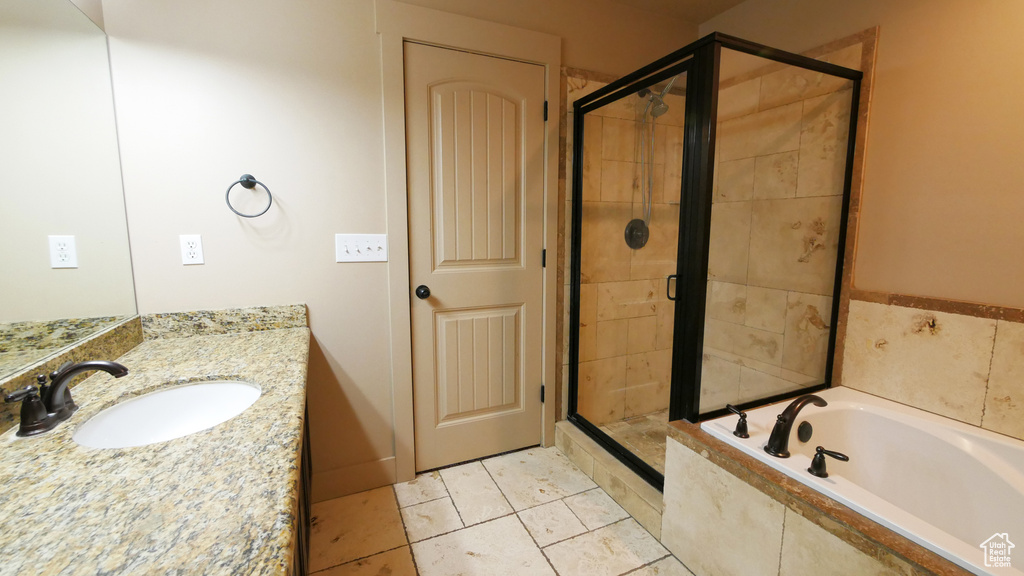 Bathroom featuring tile floors, shower with separate bathtub, and large vanity