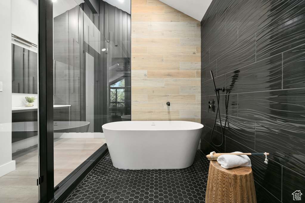 Bathroom featuring tile walls, a bath to relax in, and tile flooring