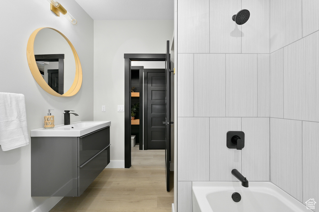 Bathroom with shower / bathing tub combination, vanity, and hardwood / wood-style floors