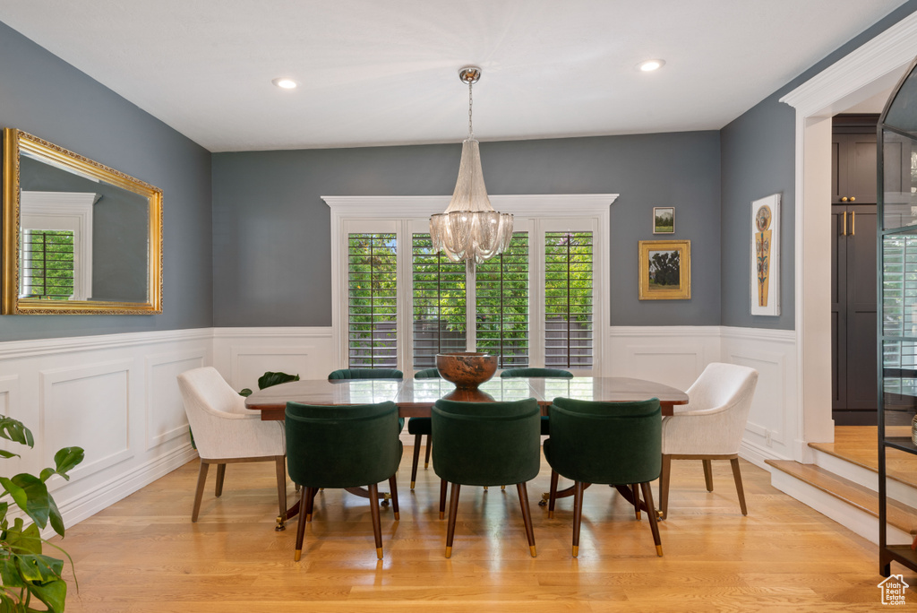 Dining room with light hardwood / wood-style floors and a notable chandelier