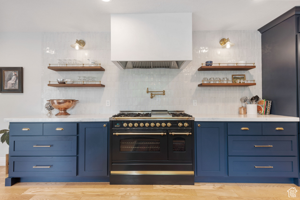 Kitchen featuring backsplash, double oven range, light hardwood / wood-style flooring, and blue cabinets