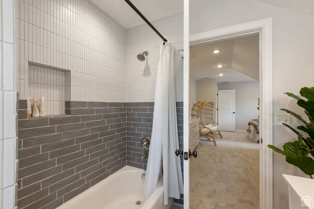 Bathroom featuring shower / bathtub combination with curtain and vaulted ceiling