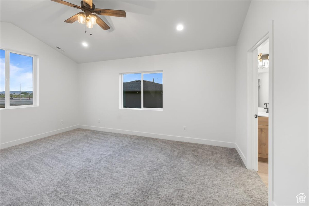 Carpeted spare room featuring lofted ceiling and ceiling fan