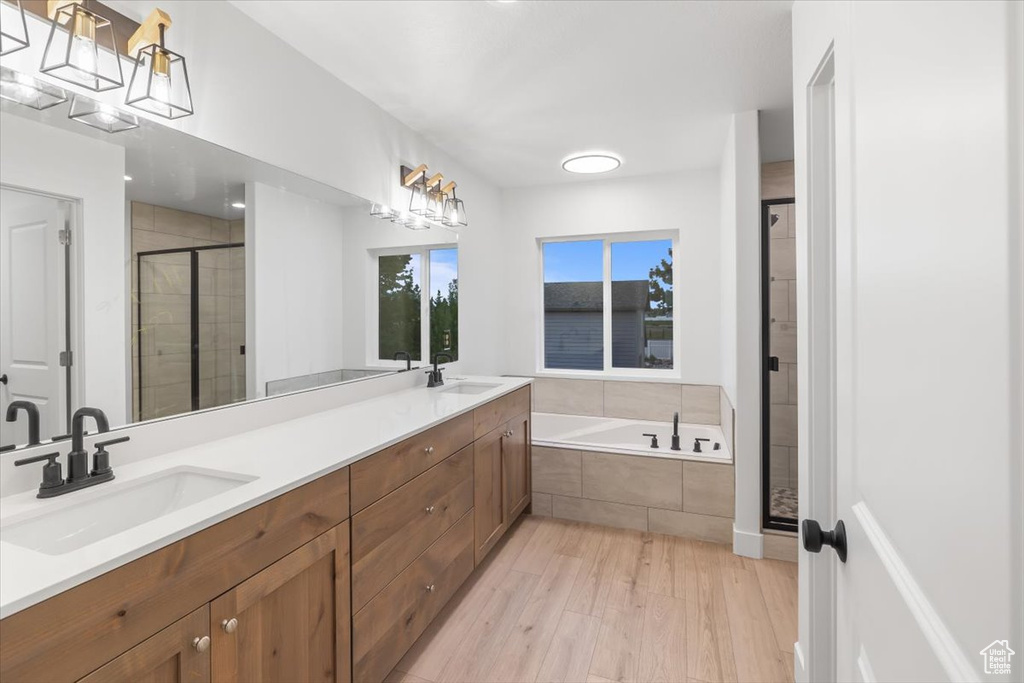 Bathroom with hardwood / wood-style flooring, double vanity, and independent shower and bath