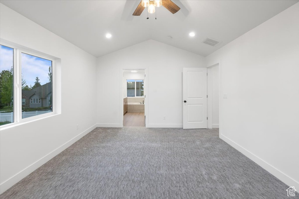Carpeted spare room with lofted ceiling, ceiling fan, and a healthy amount of sunlight