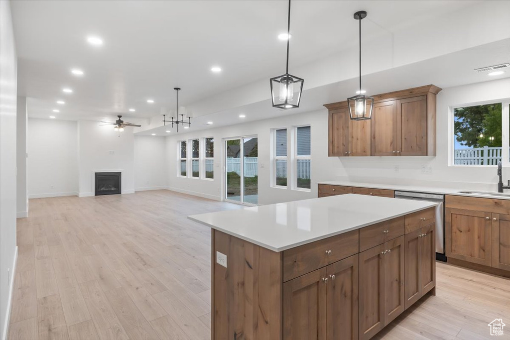 Kitchen featuring ceiling fan, a kitchen island, light wood-type flooring, stainless steel dishwasher, and pendant lighting