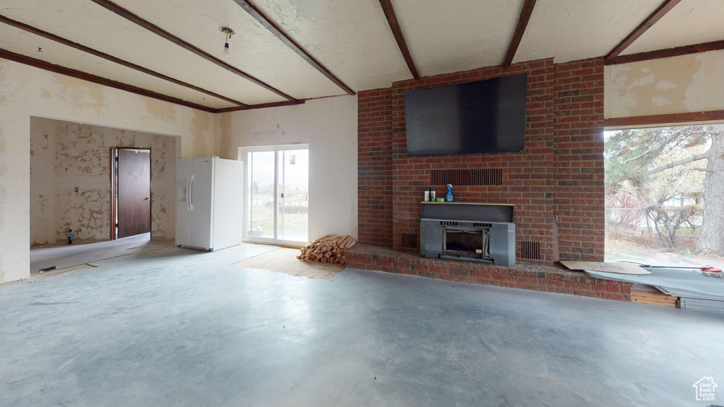 Unfurnished living room with beamed ceiling, a brick fireplace, and concrete floors