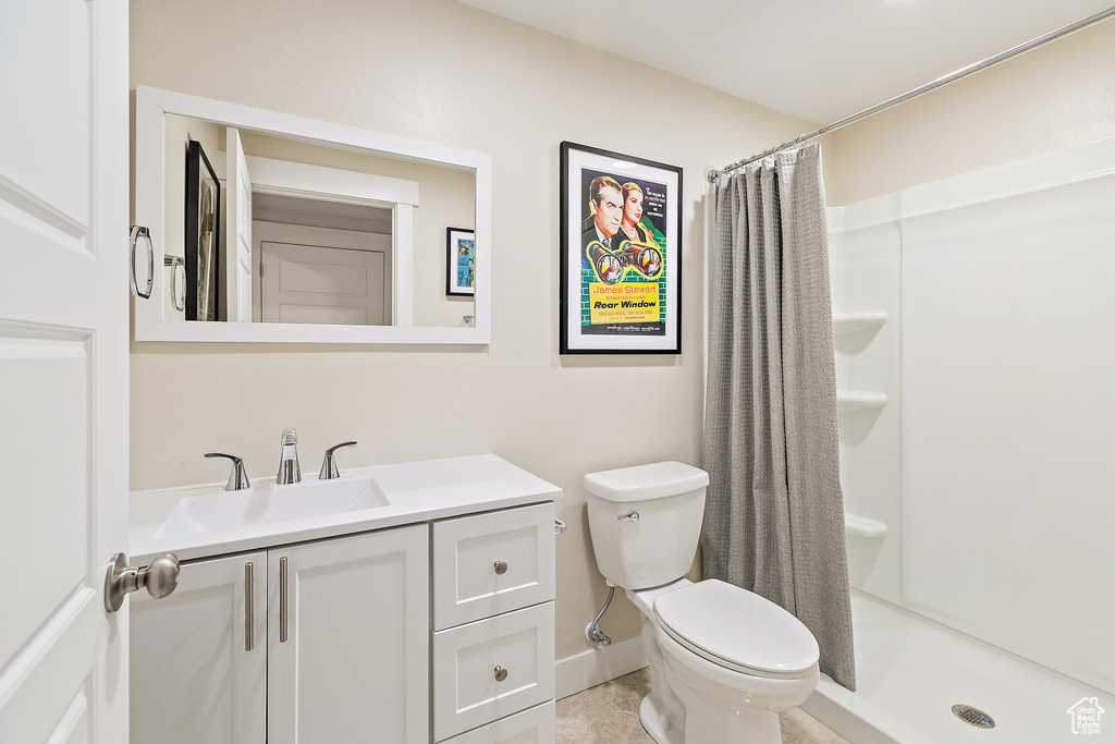 Bathroom with tile flooring, vanity, toilet, and a shower with shower curtain