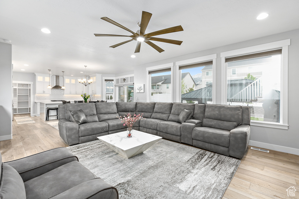 Living room featuring light hardwood / wood-style flooring and ceiling fan with notable chandelier