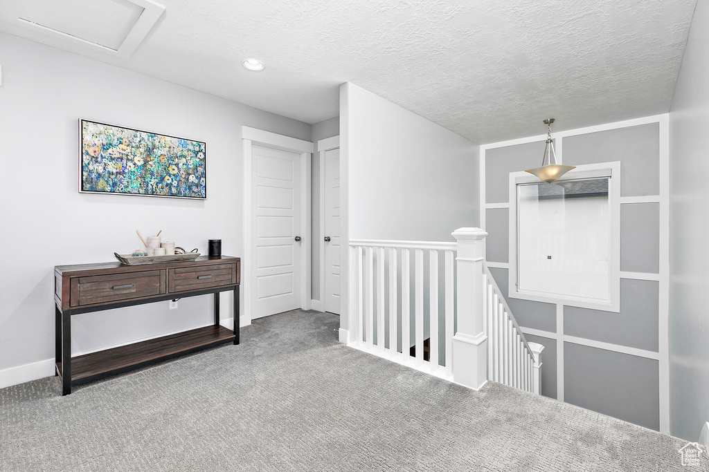 Hallway featuring a textured ceiling and carpet floors