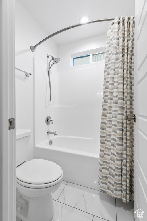 Bathroom with tile flooring, shower / bath combo, and toilet