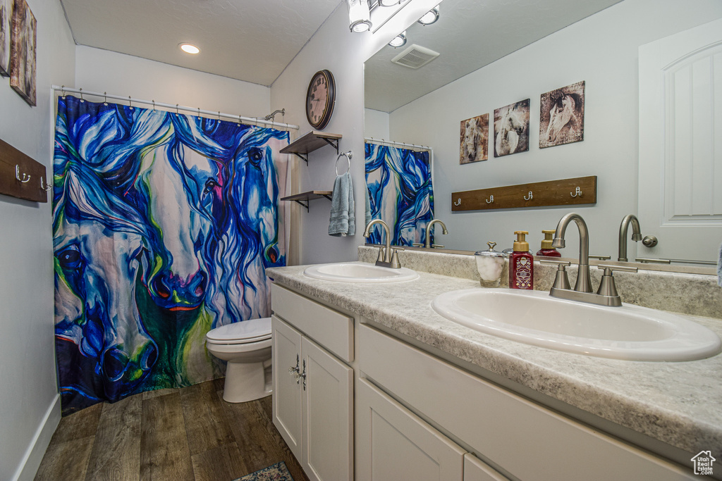 Bathroom with double vanity, hardwood / wood-style flooring, and toilet