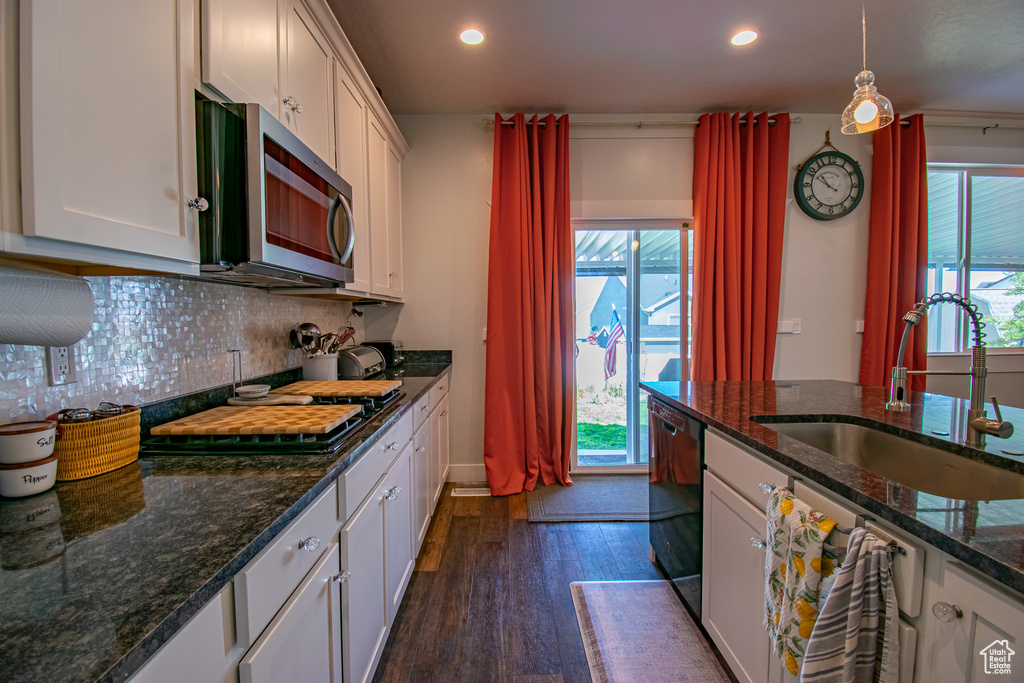 Kitchen with sink, tasteful backsplash, white cabinetry, dark stone counters, and dark hardwood / wood-style flooring