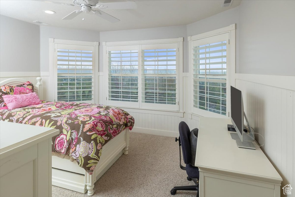 Bedroom featuring light carpet, ceiling fan, and multiple windows