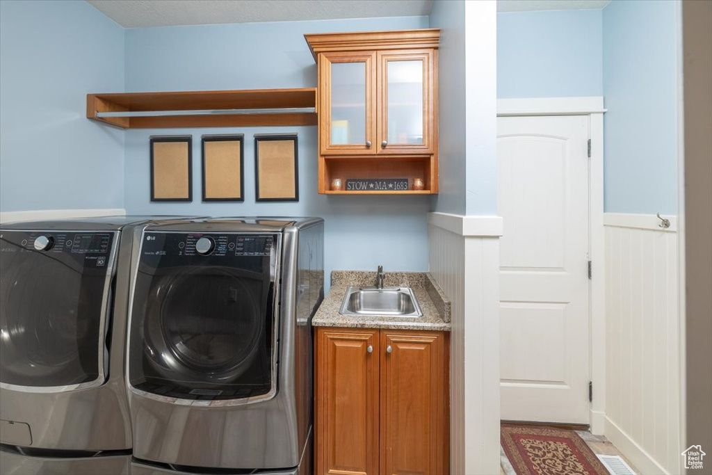 Washroom featuring cabinets, sink, and washer and dryer