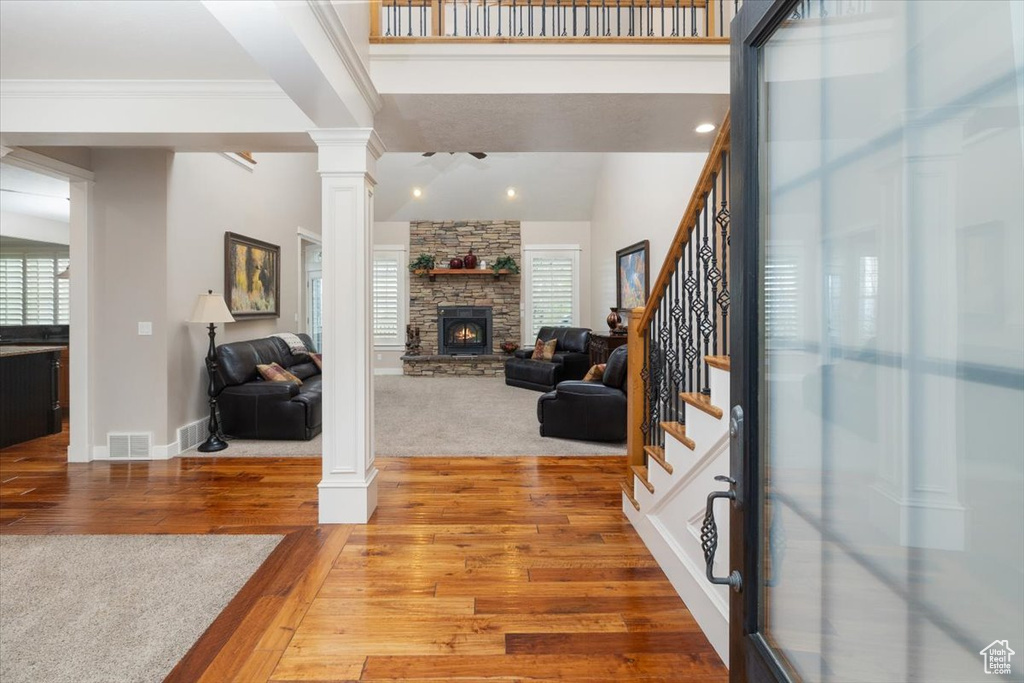 Entryway featuring a stone fireplace, wood-type flooring, and decorative columns
