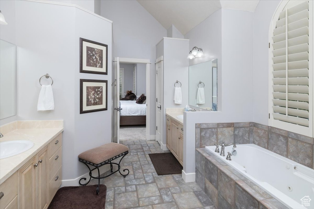 Bathroom featuring high vaulted ceiling, vanity, tile floors, and tiled bath