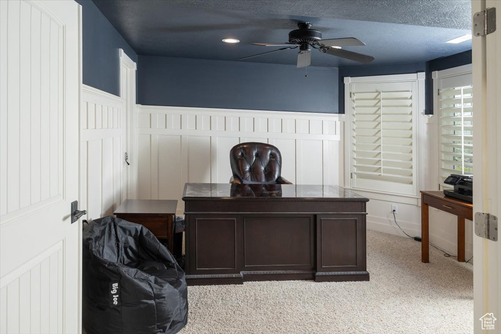 Office space with light carpet, ceiling fan, and a textured ceiling
