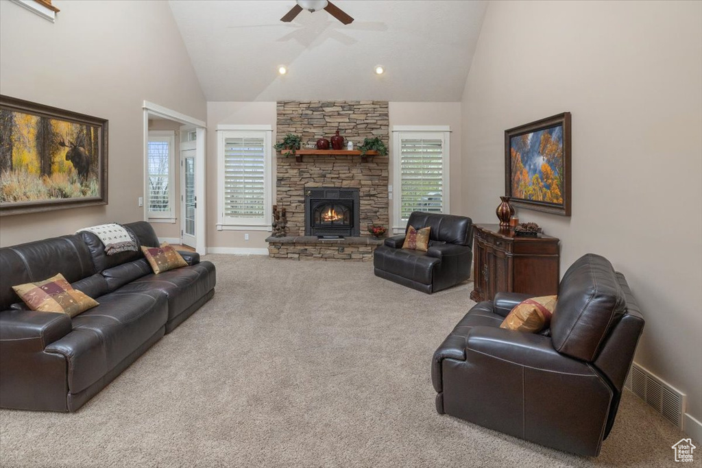 Living room featuring a healthy amount of sunlight, carpet flooring, ceiling fan, and a fireplace