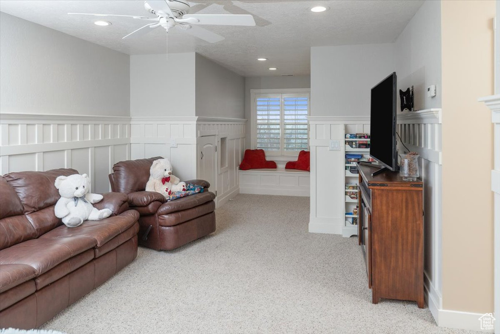 Carpeted living room featuring ceiling fan and a textured ceiling