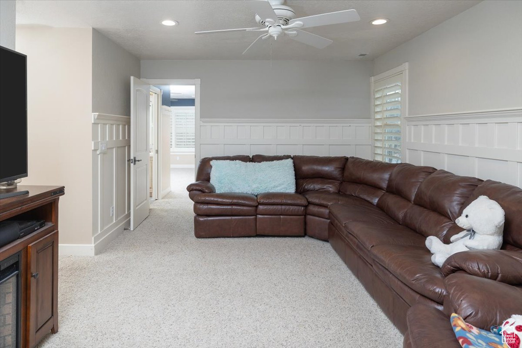 Living room featuring light colored carpet, ceiling fan, and a wealth of natural light