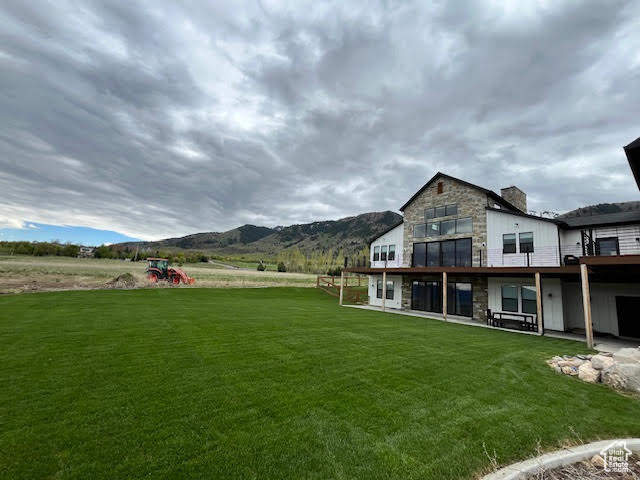 Rear view of property with a lawn, a chimney, a mountain view, and stone siding