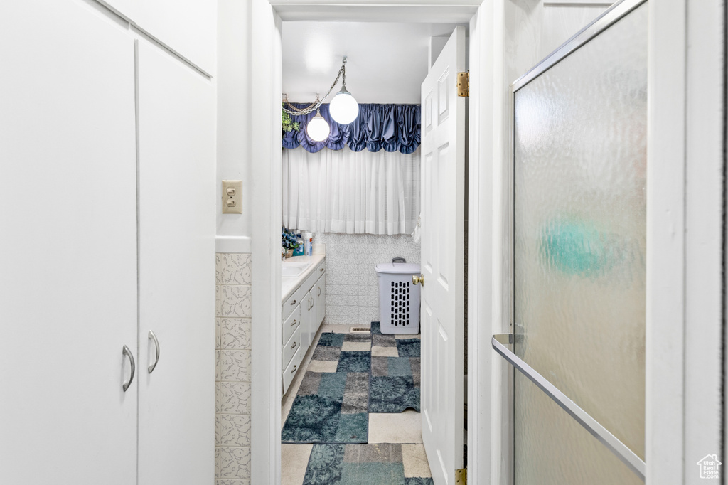 Bathroom featuring a shower with shower door, tile floors, and vanity