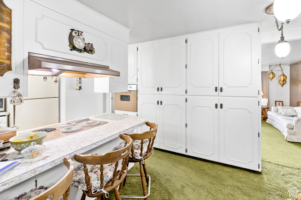 Kitchen with carpet, white fridge, and white cabinetry
