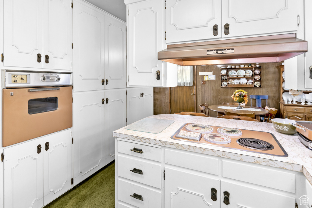 Kitchen featuring white appliances, white cabinetry, and dark colored carpet