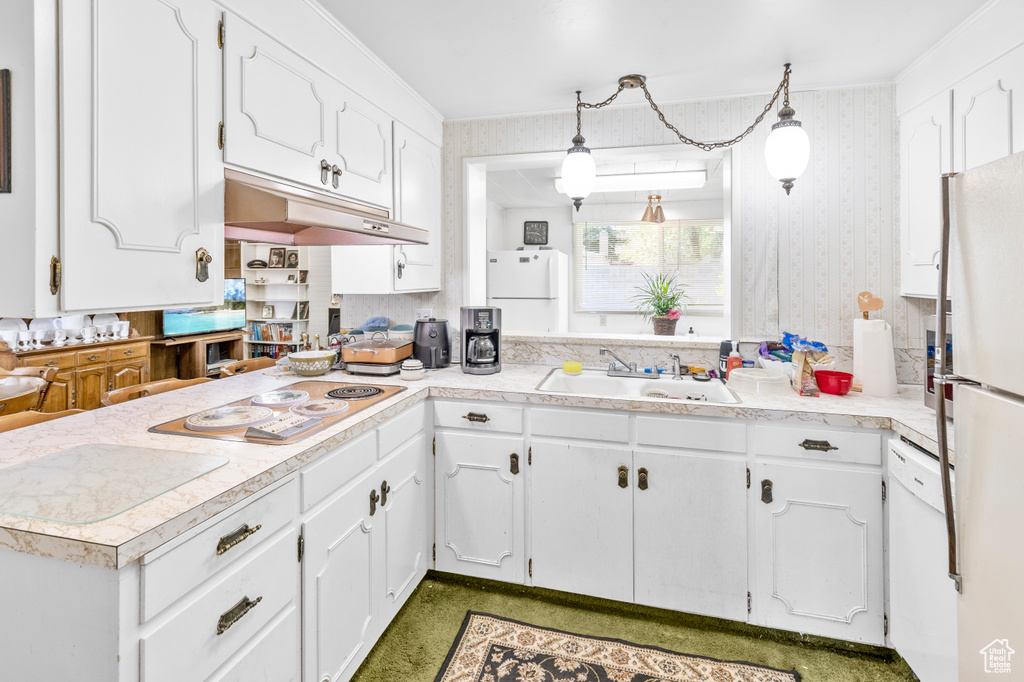 Kitchen featuring backsplash, white appliances, white cabinets, sink, and pendant lighting