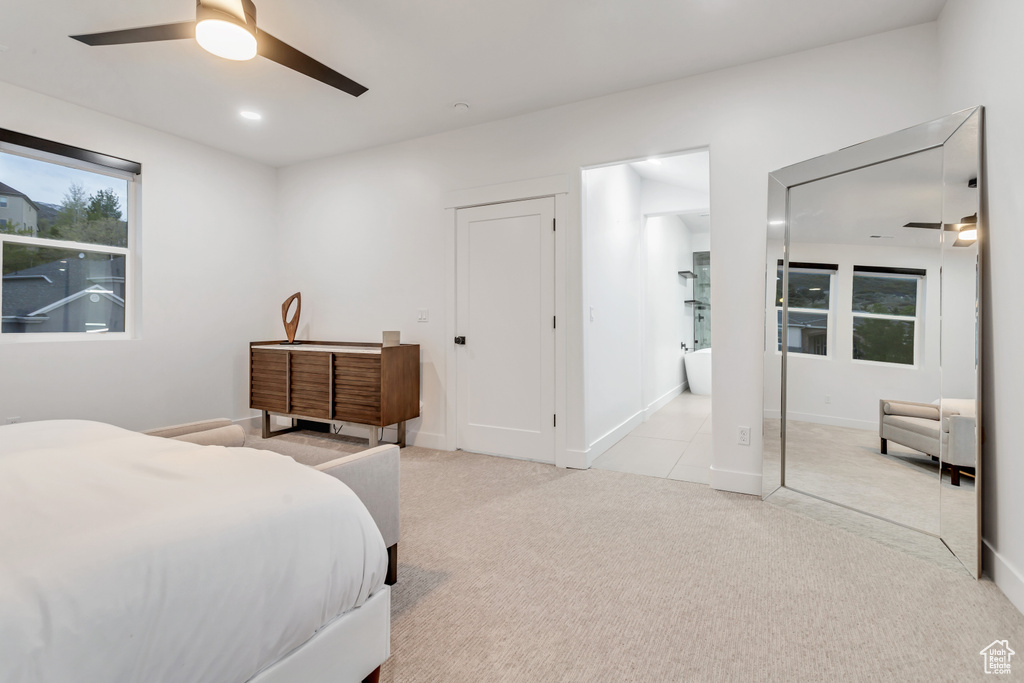 Bedroom with light colored carpet, ensuite bath, and ceiling fan